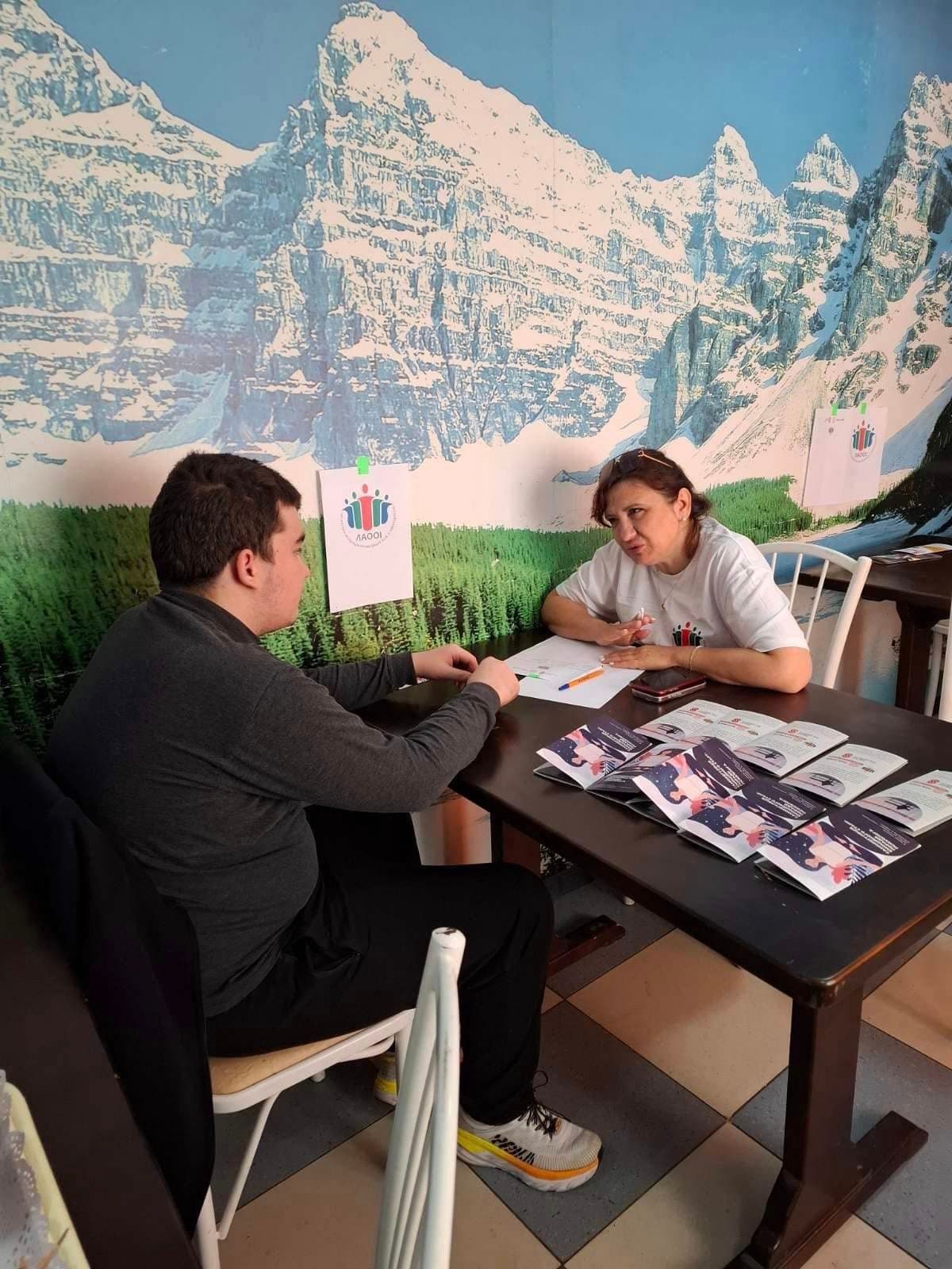 Чоловік та жінка сидять за столом, на столі розкладені листівки.