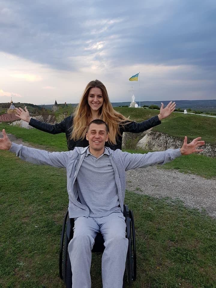 Жінка та чоловік розмахують руками на фоні прапора України.