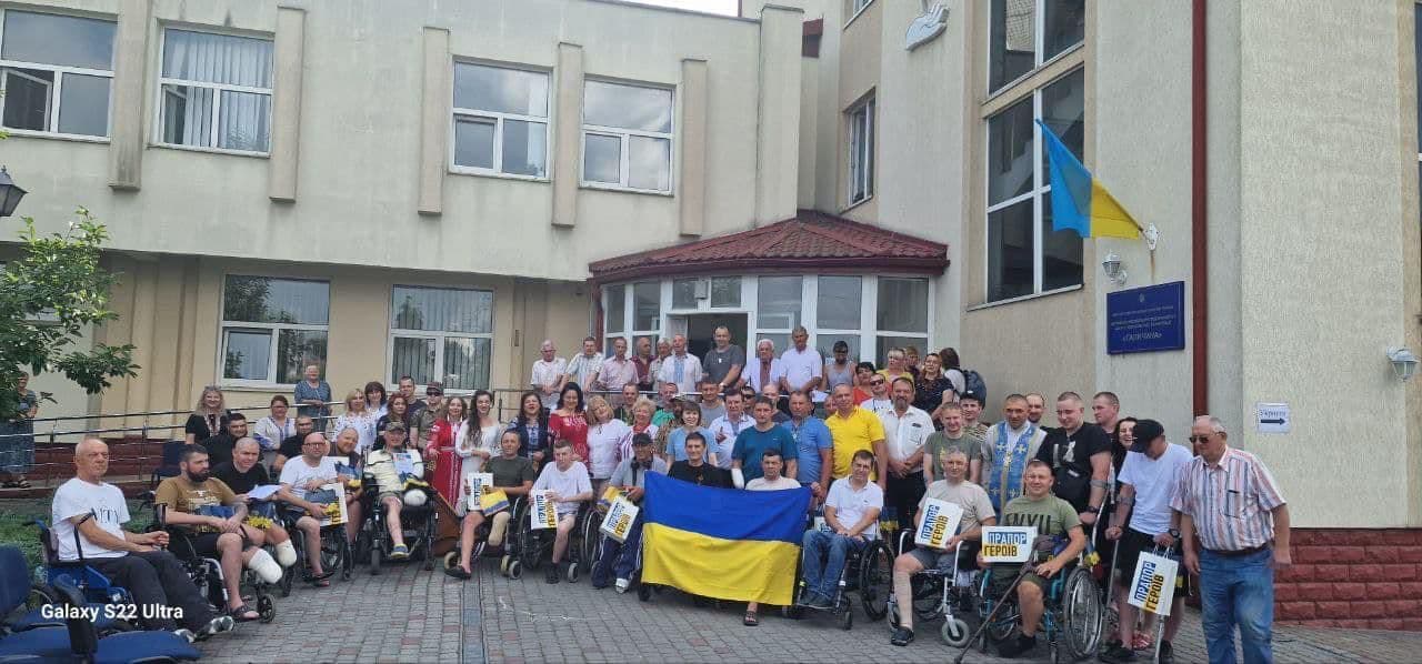 Група людей тримає прапор України.