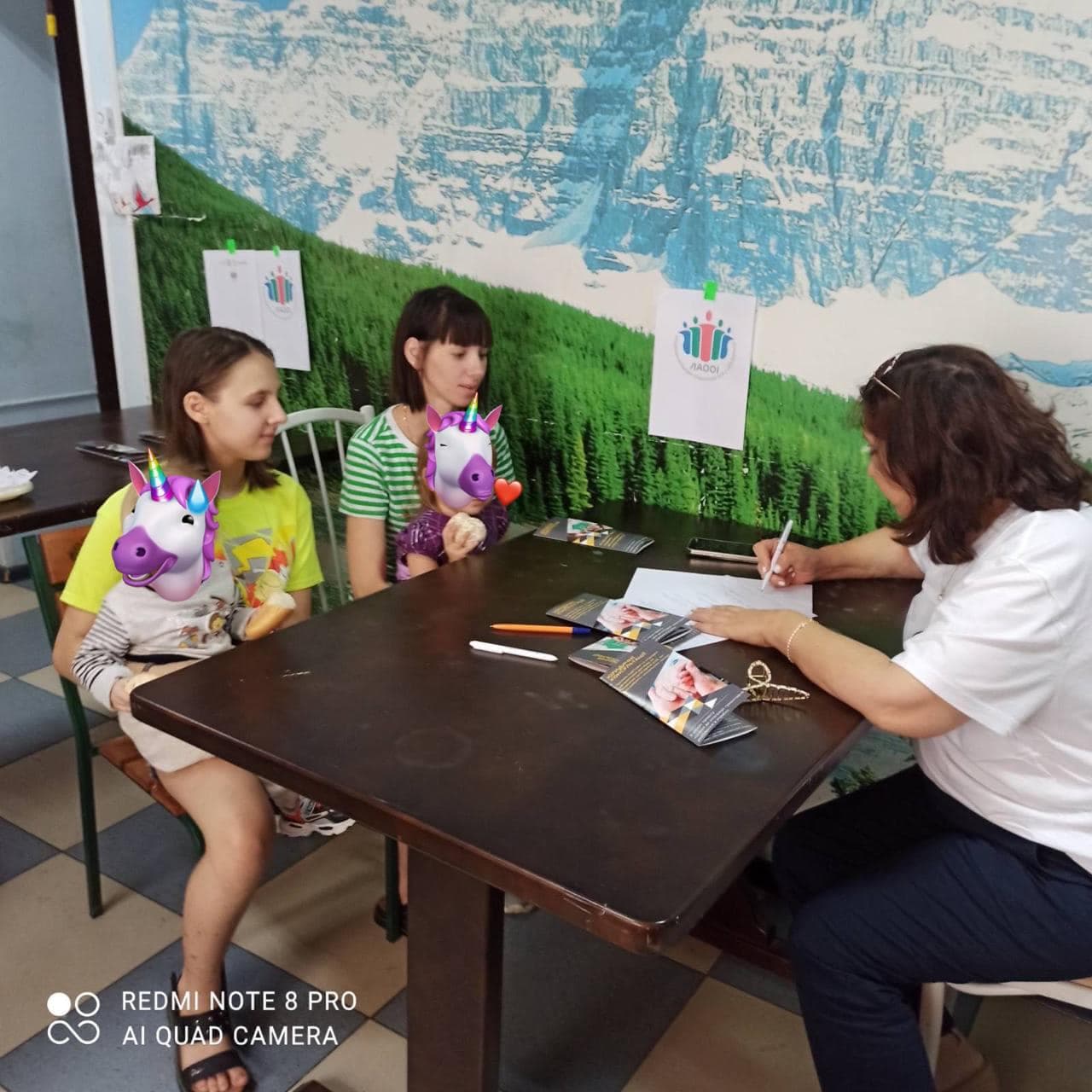 Дві дівчини та жінка сидять за столом і заповнюють анкету.