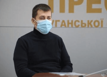 A man in a respirator mask sits at a table