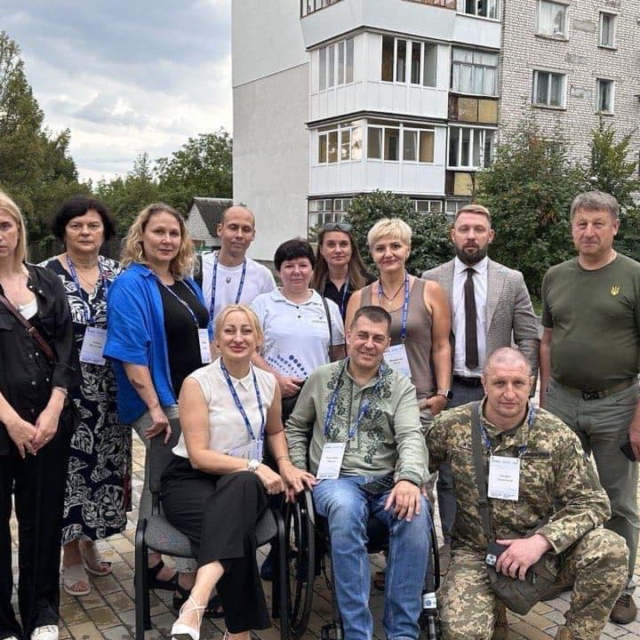 A group photo with military personnel in the yard, with a multi-story building in the background.
