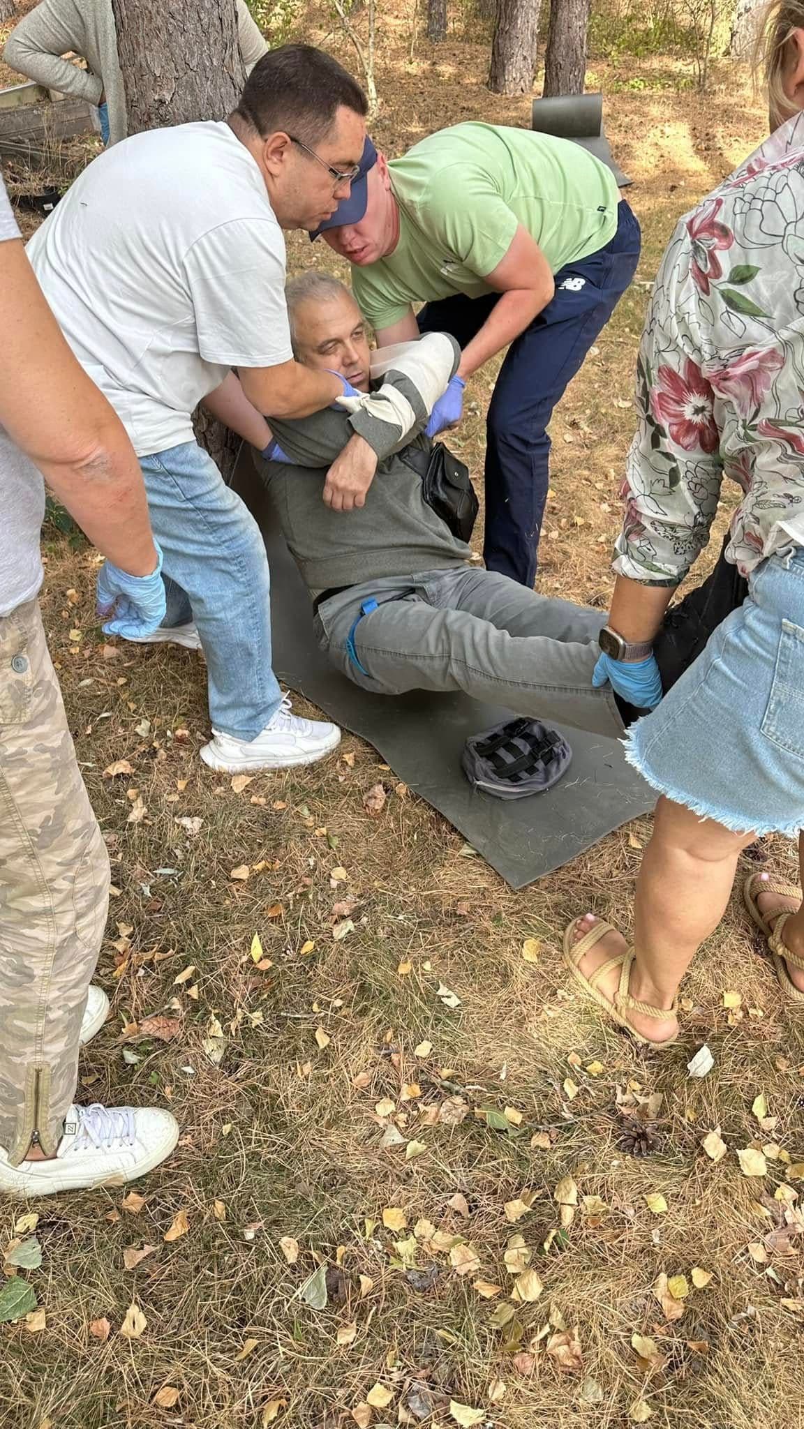 Four people are helping to lay a man on a mat.