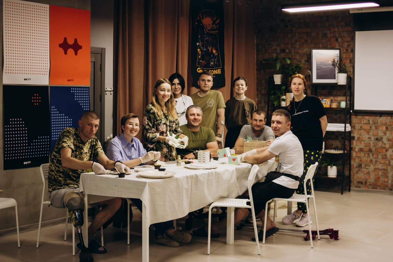 A group of people is sitting and standing at the table.