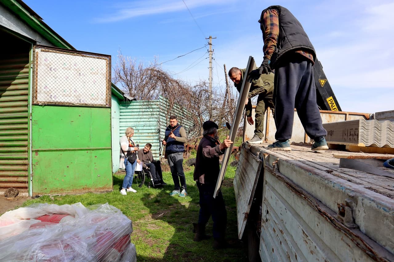 Волонтери вигружають будівельні матеріали з вантажівки для відновлення будинків у зруйнованій громаді.