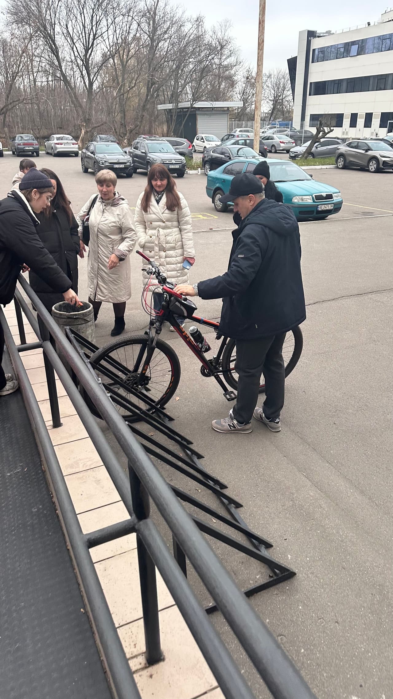 Група учасників тренінгу оглядає територію біля будівлі під час практичного заняття. На фото видно велосипедну рампу, пандус і ділянку перед входом, де учасники аналізують елементи доступності.»