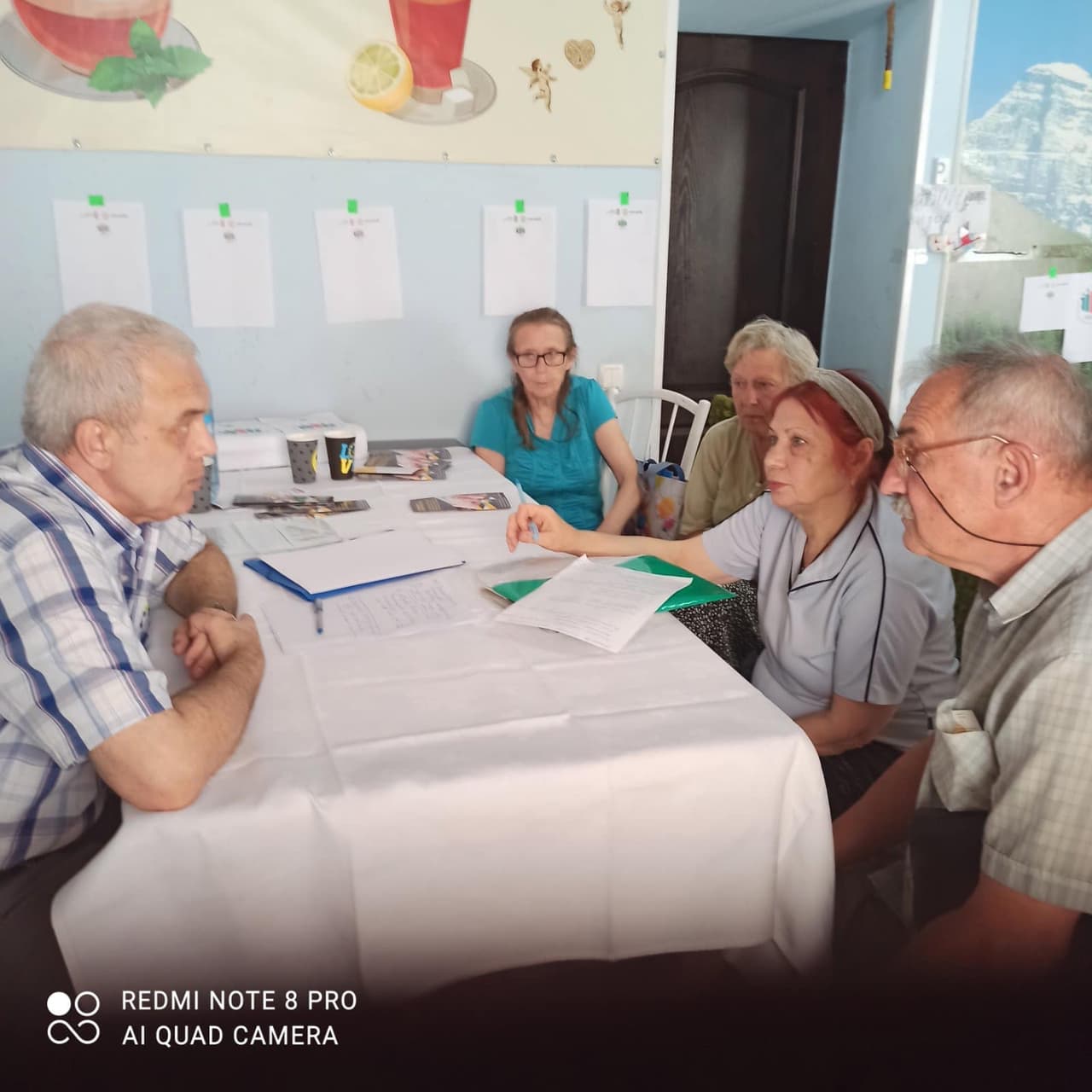 Три жінки та чоловік сидять за столом навпроти іншого чоловіка.