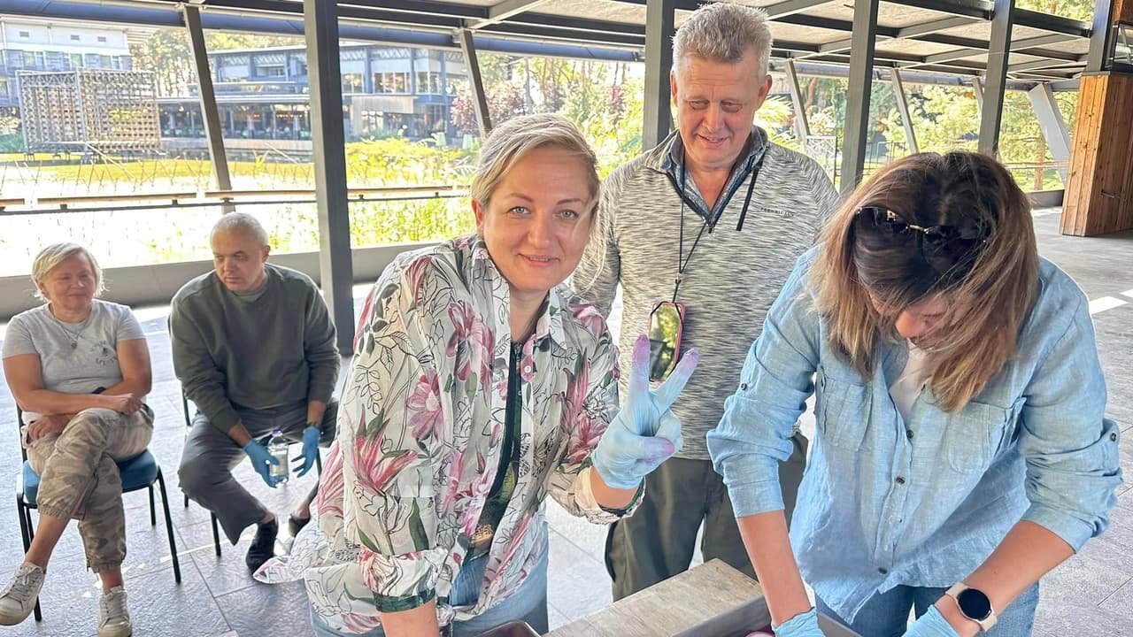 Five people in a hall stand by a table where training is being conducted.
